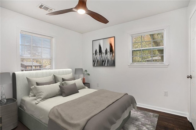 bedroom with dark wood finished floors, multiple windows, baseboards, and visible vents