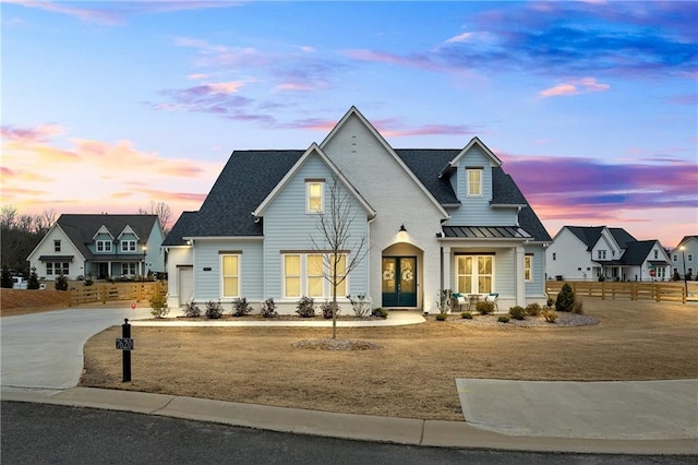modern farmhouse featuring a standing seam roof, fence, metal roof, and driveway