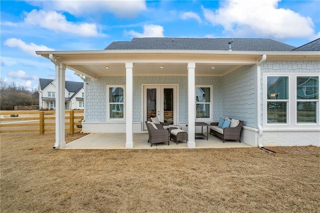 back of property with an outdoor living space, a shingled roof, a patio area, and fence