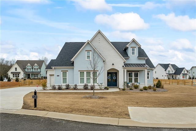 modern farmhouse style home with fence, french doors, a standing seam roof, driveway, and metal roof