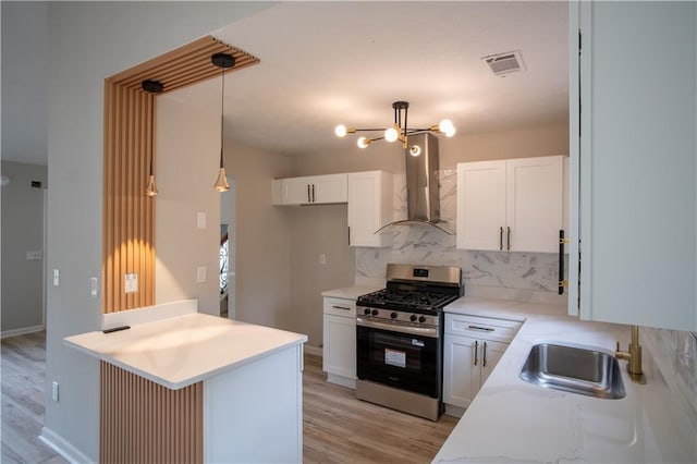 5072 Plantation View Trl, Stone Mountain, GA 30088 - kitchen with wall chimney range hood, stainless steel gas range, decorative backsplash, and light wood finished floors