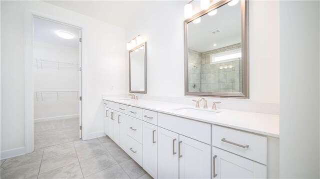 bathroom with tile patterned flooring, vanity, and tiled shower