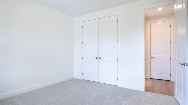 unfurnished bedroom featuring light carpet and a closet