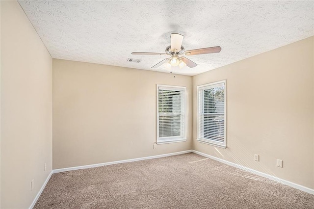 spare room featuring a textured ceiling, ceiling fan, and carpet