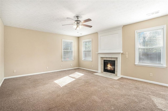 unfurnished living room with light colored carpet, a healthy amount of sunlight, a fireplace, and ceiling fan