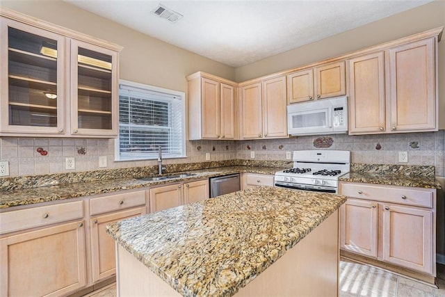 kitchen with a center island, sink, white appliances, light stone countertops, and light brown cabinetry