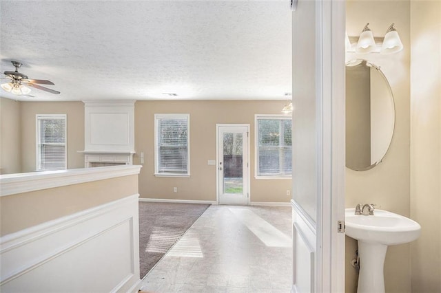 bathroom with ceiling fan, a wealth of natural light, and a textured ceiling