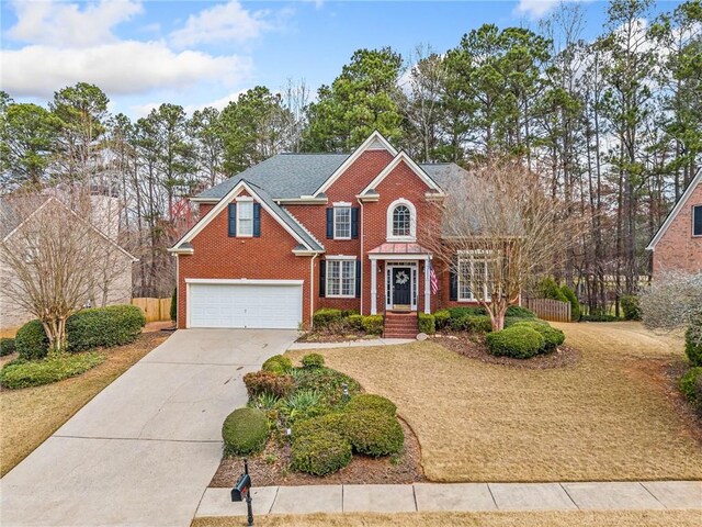 view of front facade featuring brick siding, driveway, an attached garage, and fence