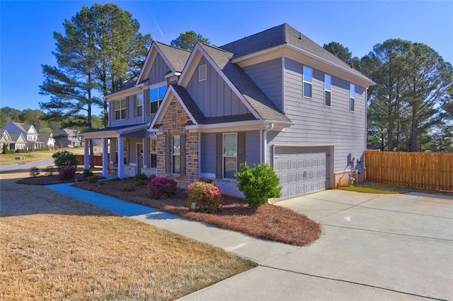 craftsman-style home with driveway, stone siding, board and batten siding, a garage, and fence