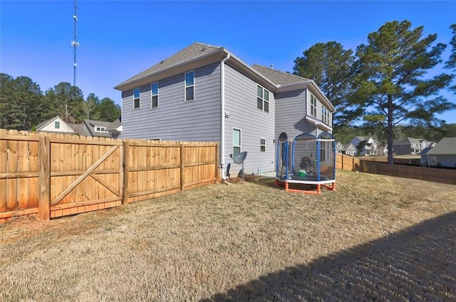 back of house with fence, a shingled roof, and a lawn