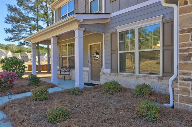 doorway to property with board and batten siding, a porch, and stone siding
