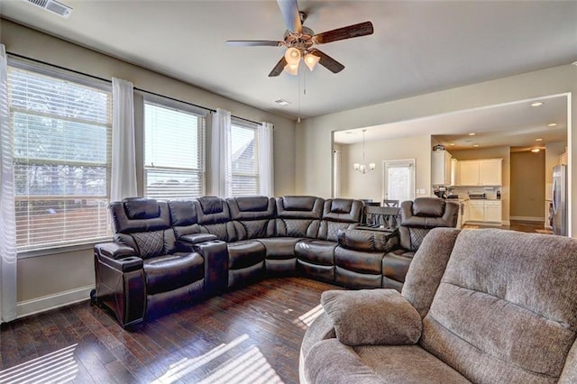 living room featuring a wealth of natural light, dark wood-style floors, baseboards, and ceiling fan with notable chandelier