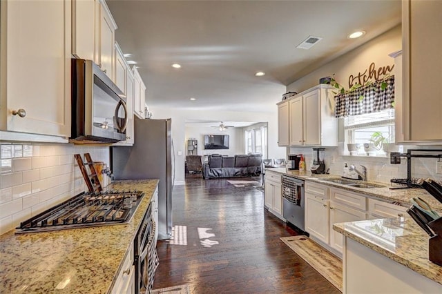 kitchen featuring visible vents, a sink, open floor plan, appliances with stainless steel finishes, and dark wood-type flooring