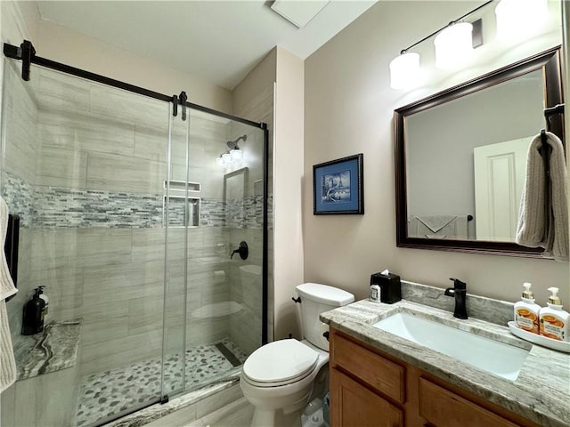 full bath featuring toilet, a stall shower, and vanity