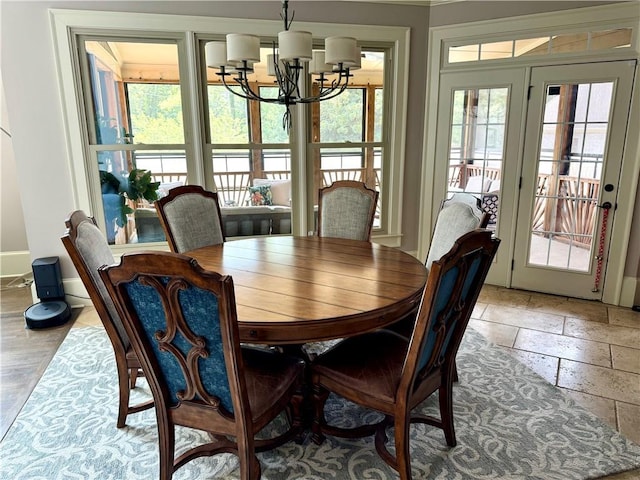 dining room with stone tile floors, a chandelier, and baseboards