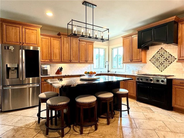 kitchen featuring light stone counters, appliances with stainless steel finishes, brown cabinets, a center island, and a sink