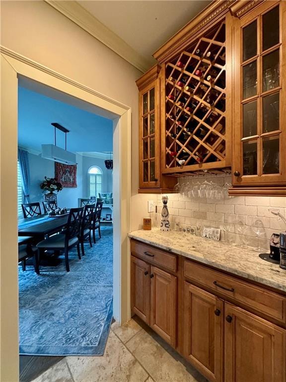 bar featuring crown molding, a dry bar, light colored carpet, hanging light fixtures, and decorative backsplash