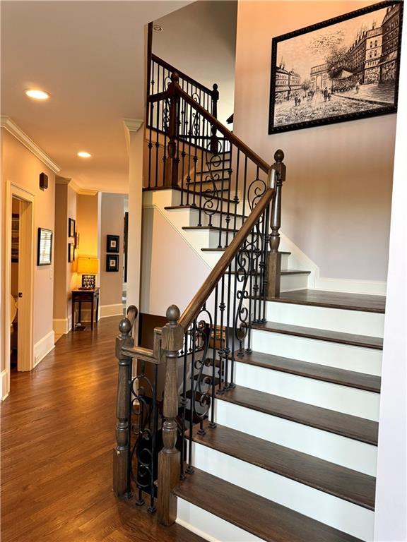 stairway with ornamental molding, recessed lighting, wood finished floors, and baseboards