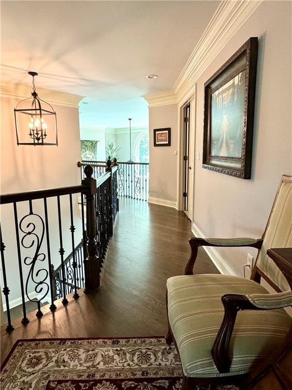 hall with ornamental molding, dark wood-type flooring, a notable chandelier, and baseboards