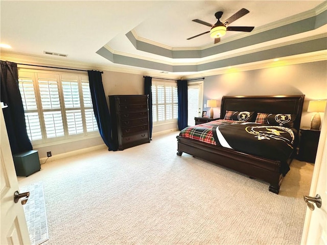 bedroom with a tray ceiling, visible vents, ornamental molding, light carpet, and baseboards