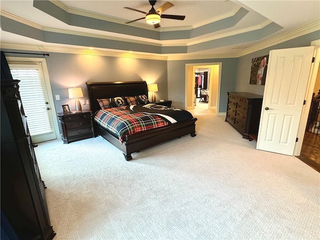 bedroom with ornamental molding, a tray ceiling, light carpet, and a ceiling fan