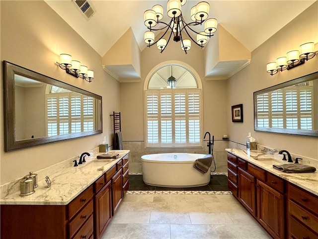 bathroom with vaulted ceiling, visible vents, a freestanding tub, and vanity