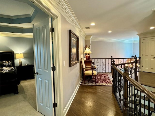 hallway featuring wood finished floors, an upstairs landing, visible vents, baseboards, and ornamental molding