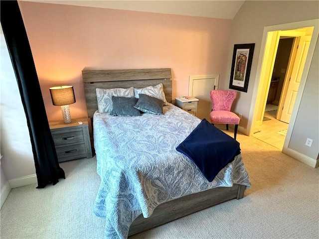 bedroom with lofted ceiling, light colored carpet, and baseboards