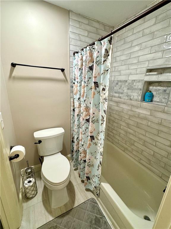 full bath featuring toilet, shower / tub combo, and tile patterned floors