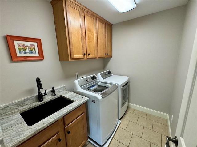 clothes washing area featuring washing machine and clothes dryer, light tile patterned floors, cabinet space, a sink, and baseboards