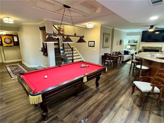 recreation room featuring ornamental molding, ceiling fan, a stone fireplace, and dark wood-style floors