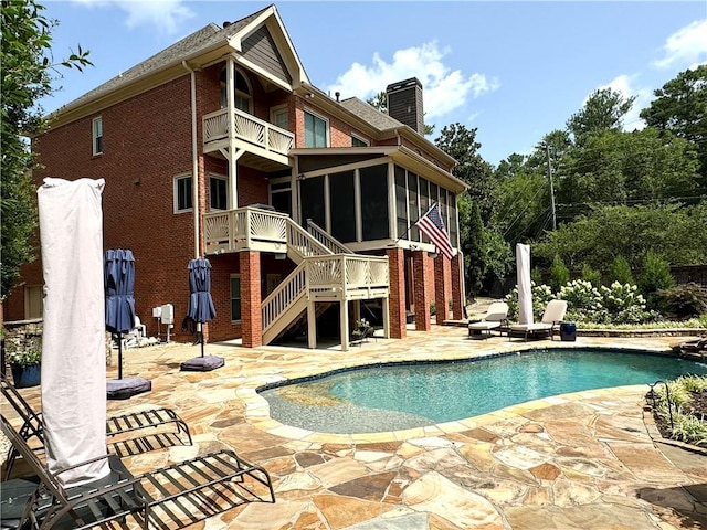 pool with a sunroom, stairway, and a patio