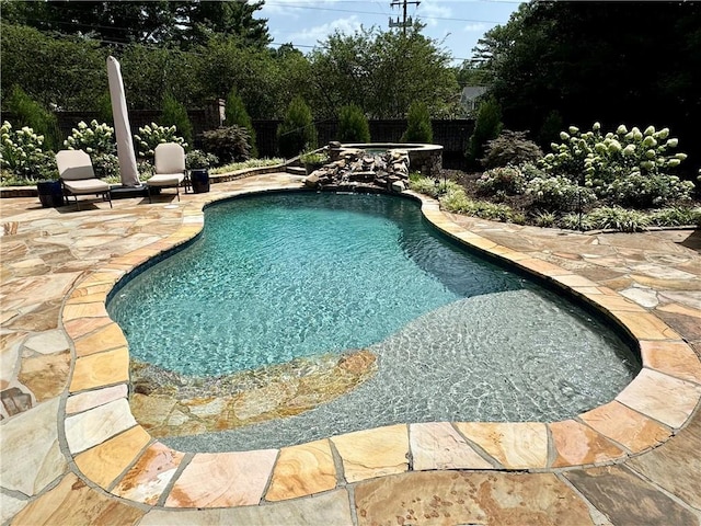 pool with a patio area, fence, and an in ground hot tub