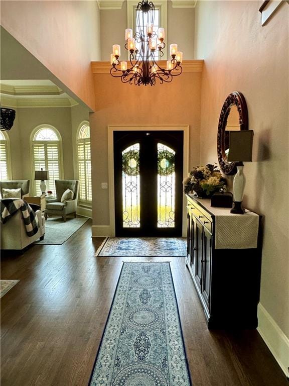 foyer entrance featuring dark wood-style floors, baseboards, a chandelier, and crown molding