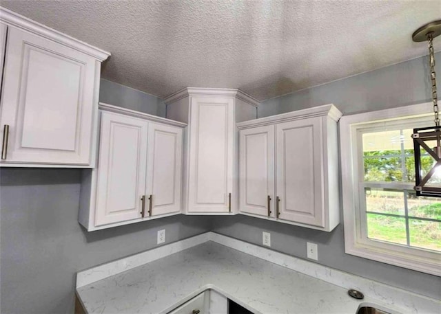 kitchen featuring a textured ceiling and white cabinets