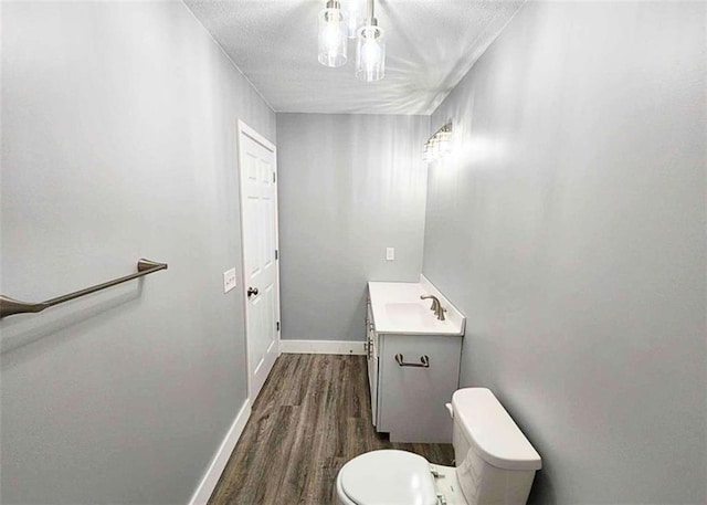 bathroom featuring hardwood / wood-style flooring, vanity, a textured ceiling, and toilet