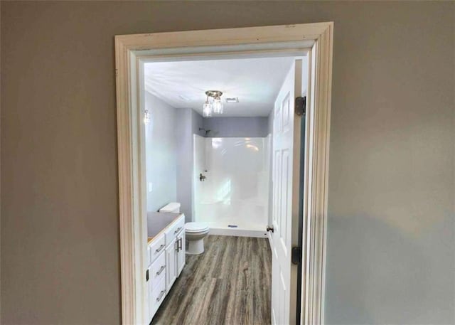 bathroom featuring walk in shower, vanity, toilet, and hardwood / wood-style flooring