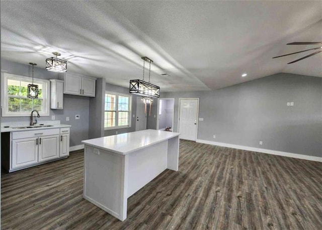 kitchen featuring sink, decorative light fixtures, white cabinets, and a kitchen island