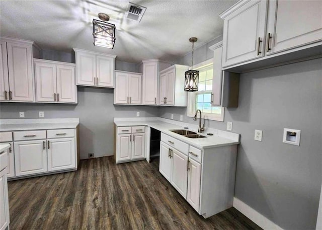 kitchen featuring dark hardwood / wood-style floors, sink, white cabinets, hanging light fixtures, and a textured ceiling