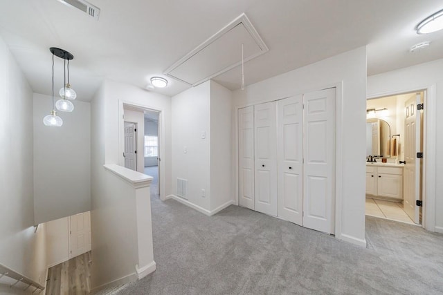 hall featuring light carpet, an upstairs landing, attic access, and visible vents