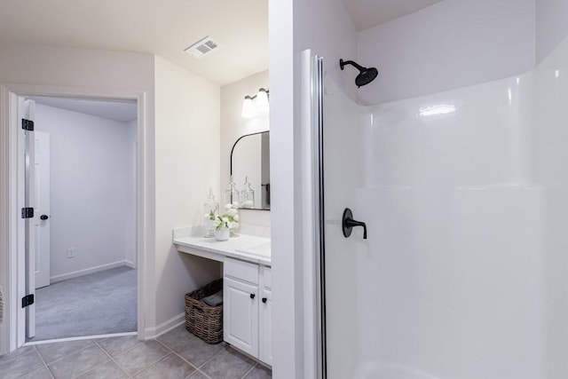 bathroom with tile patterned flooring, visible vents, baseboards, vanity, and a shower