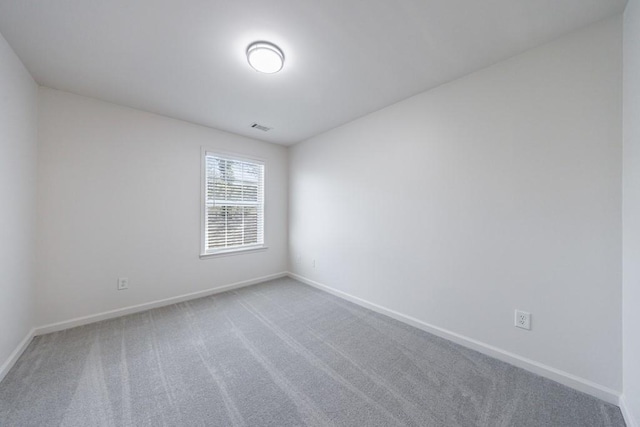 spare room featuring baseboards, visible vents, and carpet floors