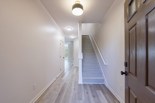 stairway with wood finished floors, baseboards, and ornamental molding