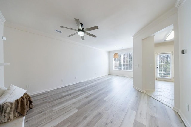 unfurnished room with a ceiling fan, baseboards, visible vents, ornamental molding, and light wood-style floors