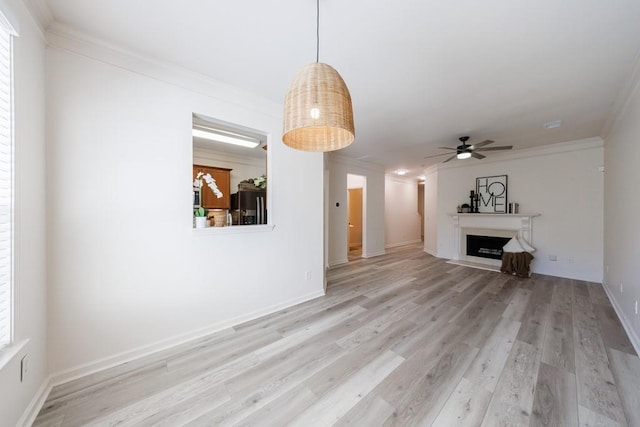 unfurnished living room featuring crown molding, baseboards, a fireplace, light wood-style floors, and a ceiling fan