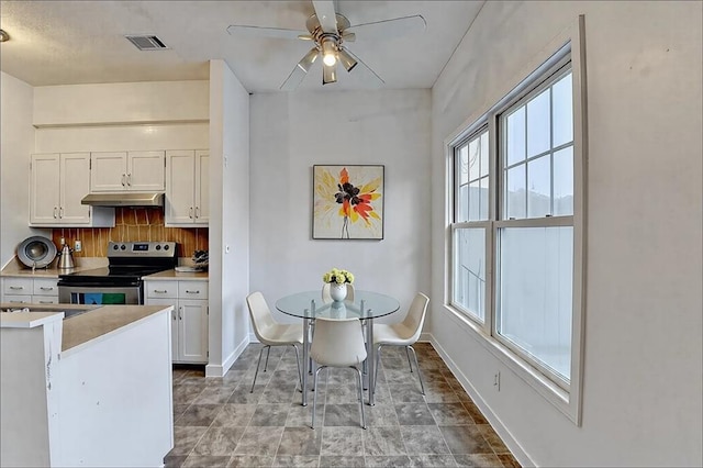 kitchen featuring light countertops, white cabinetry, under cabinet range hood, and stainless steel electric stove