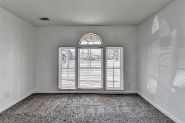 carpeted empty room featuring visible vents and baseboards