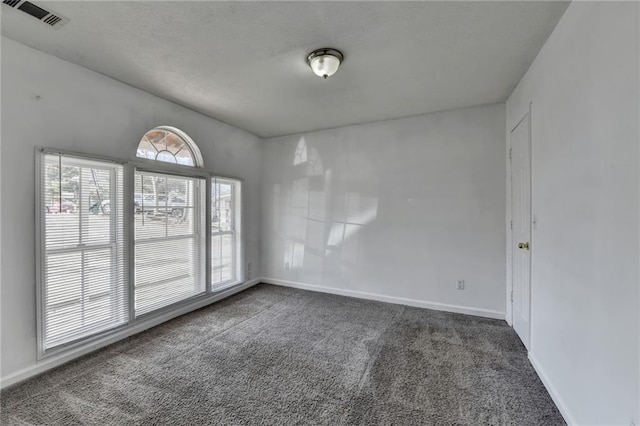 empty room featuring dark colored carpet, visible vents, and baseboards