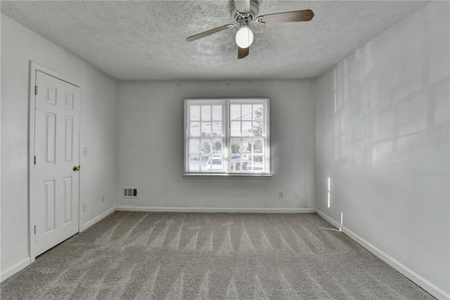 spare room with light carpet, visible vents, baseboards, and a textured ceiling