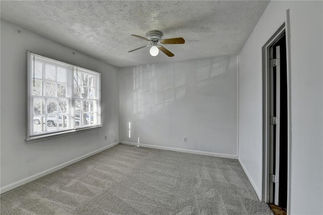 spare room with a ceiling fan, baseboards, a textured ceiling, and light colored carpet